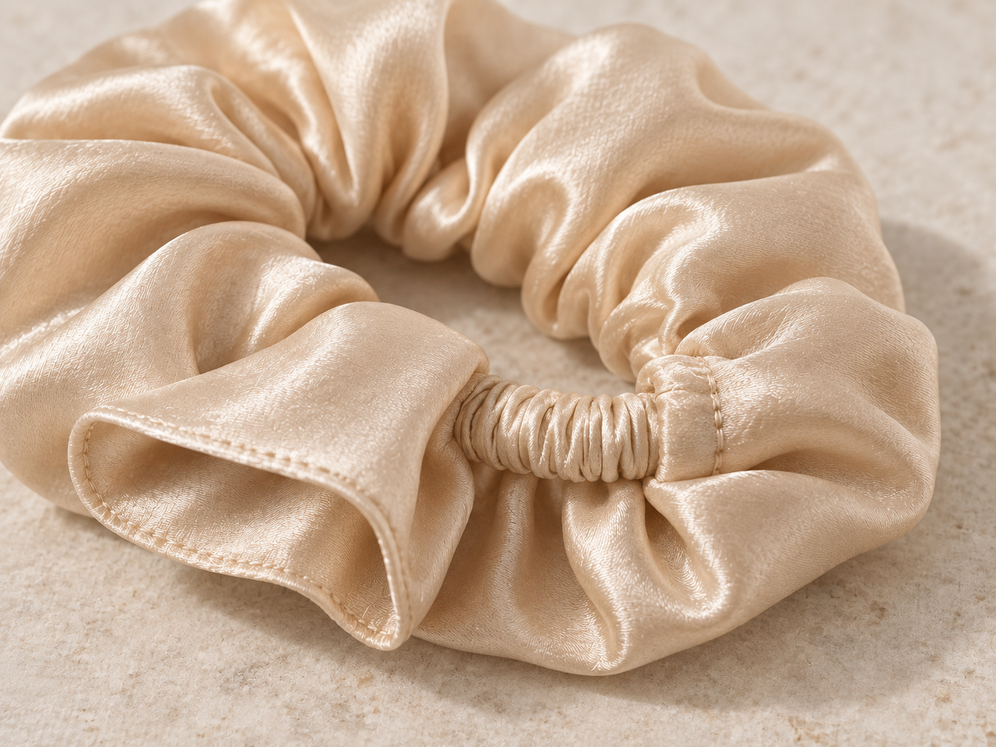 Close-up of champagne silk scrunchie gathered fabric, covered elastic and clean seam